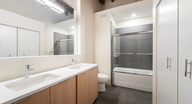 Contemporary bathroom with a double vanity, large mirror, and a shower-tub combination at Cobbler Square Lofts in Chicago