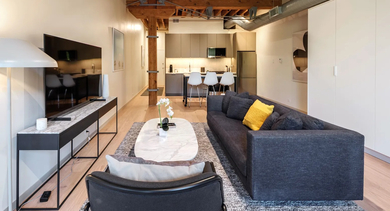 An open-plan living space seamlessly connecting a cozy lounge area and a stylish modern kitchen at Cobbler Square Lofts in Chicago