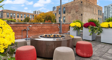 Inviting rooftop lounge area with a cozy fire pit and city views at Cobbler Square Lofts in Chicago