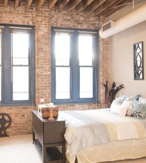 Spacious bedroom with contemporary furniture, neutral decor, and a comfortable setup at Cobbler Square Lofts in Chicago