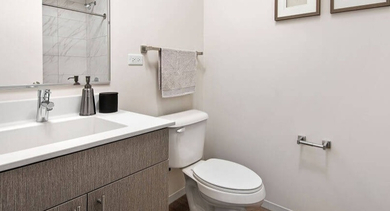 Contemporary bathroom with a single vanity, clean design, and framed art on the wall at Coeval Apartments in Chicago