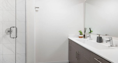 Bright and modern bathroom featuring a walk-in shower and a contemporary double vanity at Coeval Apartments in Chicago