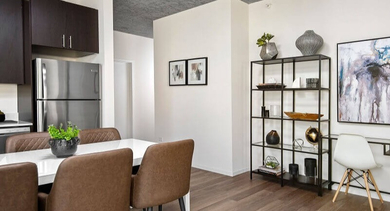 Modern open-plan dining area and kitchen with dark wood cabinets and stylish decor at Coeval Apartments in Chicago