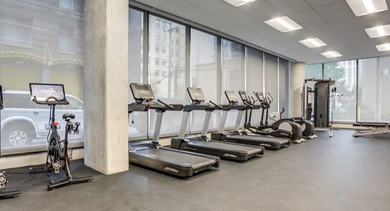 Well-equipped fitness center featuring a range of cardio machines including treadmills and spin bikes at Coeval Apartments in Chicago