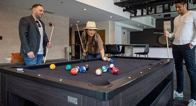 Residents enjoying a game of billiards in the stylishly designed game room at Coeval Apartments in Chicago
