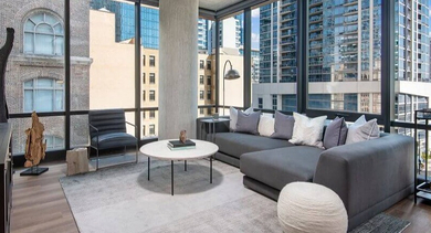 Spacious living room with a large gray sectional sofa, modern decor, and expansive city views at Coeval Apartments in Chicago