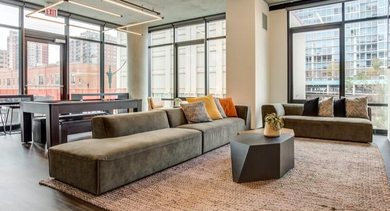 Expansive resident lounge with a billiards table, ample seating, and large windows providing natural light at Coeval Apartments in Chicago