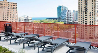 Rooftop lounge area featuring several comfortable lounge chairs and panoramic cityscape views at Coeval Apartments in Chicago