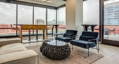 Chic rooftop lounge area with comfortable sofas, accent chairs, and panoramic city views at Coeval Apartments in Chicago