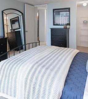 Cozy bedroom with a comfortable bed, black furniture, and soft blue walls at Columbus Plaza