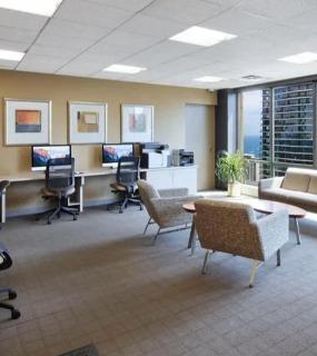 Spacious business center with computer stations, a lounge area, and large windows with city views at Columbus Plaza