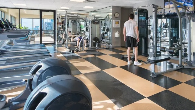 A well-equipped fitness center with various cardio and weight training machines and a checkered floor