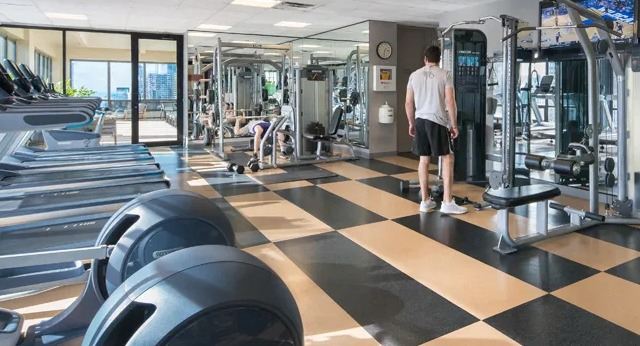 A well-equipped fitness center with various cardio and weight training machines and a checkered floor