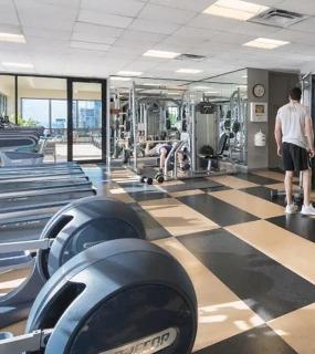 Fully equipped fitness center with treadmills, strength training equipment, and natural light at Columbus Plaza