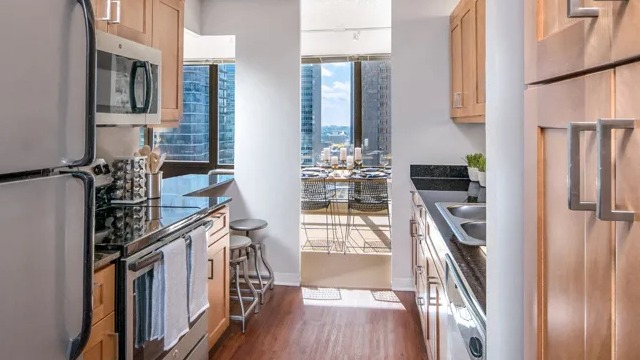 A well-appointed galley kitchen with wood cabinets, stainless steel appliances, and a glimpse of a dining area