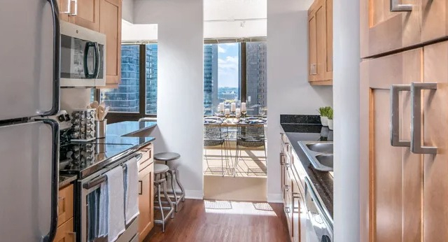 A well-appointed galley kitchen with wood cabinets, stainless steel appliances, and a glimpse of a dining area