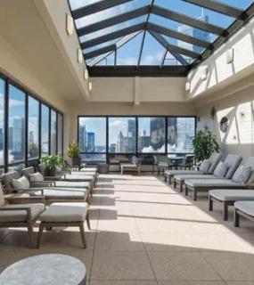 Indoor rooftop lounge with a glass skylight, modern recliners, and panoramic city views at Columbus Plazs