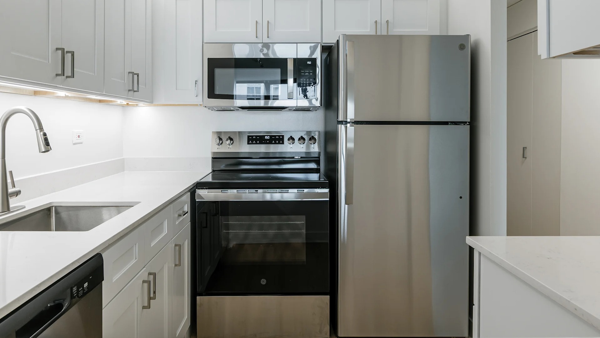 A bright modern kitchen with white cabinets, stainless steel appliances, and a clean countertop in Columbus Plaza