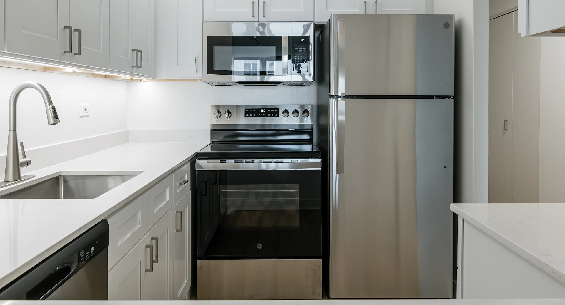 A bright modern kitchen with white cabinets, stainless steel appliances, and a clean countertop in Columbus Plaza