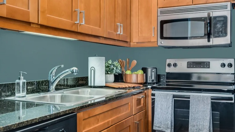 A functional kitchen with warm wood cabinets, dark countertops, and stainless steel appliances