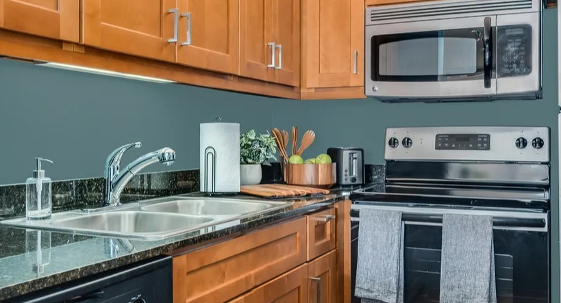 A functional kitchen with warm wood cabinets, dark countertops, and stainless steel appliances