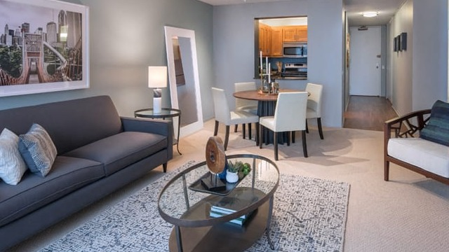 A contemporary living and dining area with a comfortable sofa, dining table, and large window views