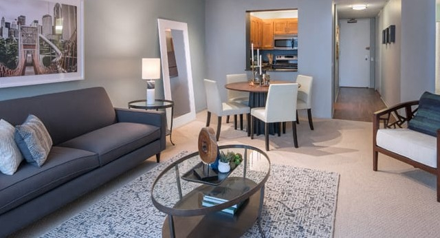 A contemporary living and dining area with a comfortable sofa, dining table, and large window views