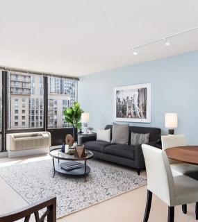Spacious living room with modern decor, large windows offering city views, and a cozy dining area at Columbus Plaza