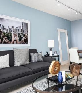 Bright and spacious living room with a dining area, modern decor, and soft blue walls at Columbus Plaza