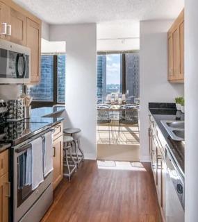 Sleek kitchen with wooden cabinets, stainless steel appliances, and a view of the dining area at Columbus Plaza