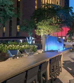Outdoor dining area with modern furniture, a waterfall feature, and ambient lighting at Columbus Plaza