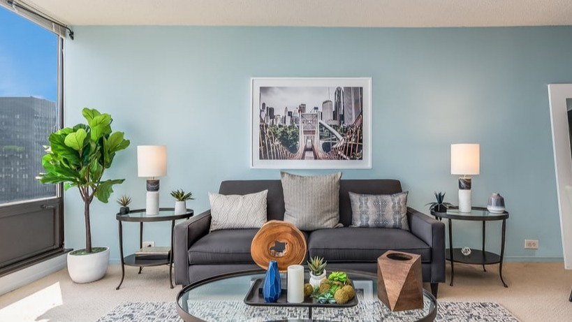 A well-appointed living room featuring a sofa, large plant, and city views from expansive windows