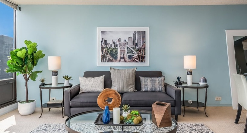 A well-appointed living room featuring a sofa, large plant, and city views from expansive windows