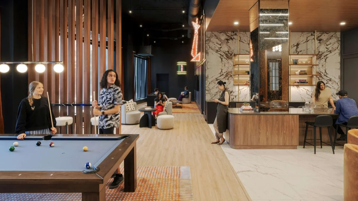 Lively amenity lounge at Coppia apartments in Chicago with a pool table, modern bar, and comfortable seating