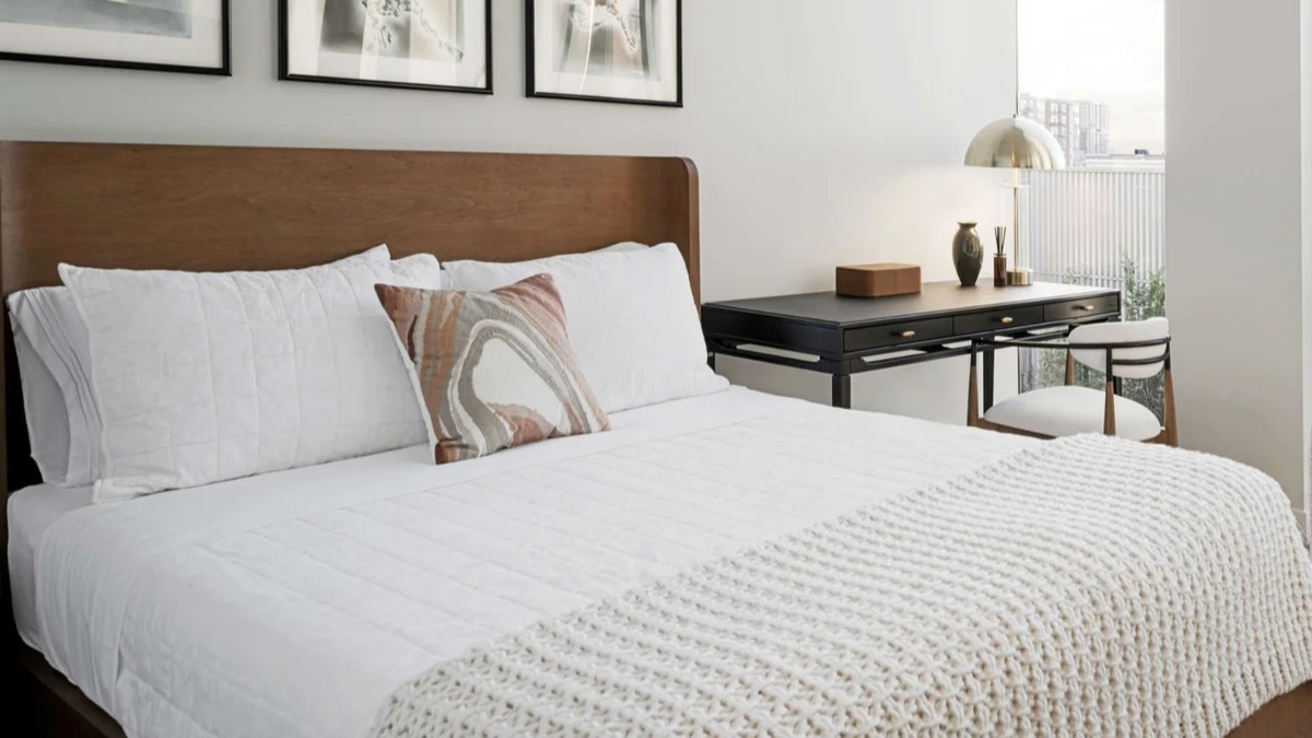 Cozy bedroom at Coppia apartments in Chicago featuring a comfortable bed, stylish artwork, and large windows with city views