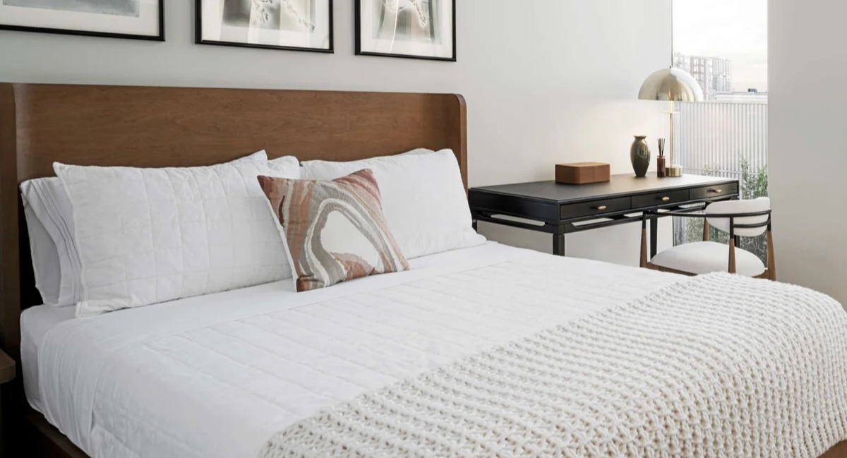 Cozy bedroom at Coppia apartments in Chicago featuring a comfortable bed, stylish artwork, and large windows with city views