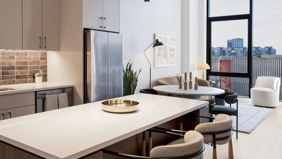 Modern apartment kitchen and dining area at Coppia in Chicago, featuring a spacious island, sleek appliances, and city views