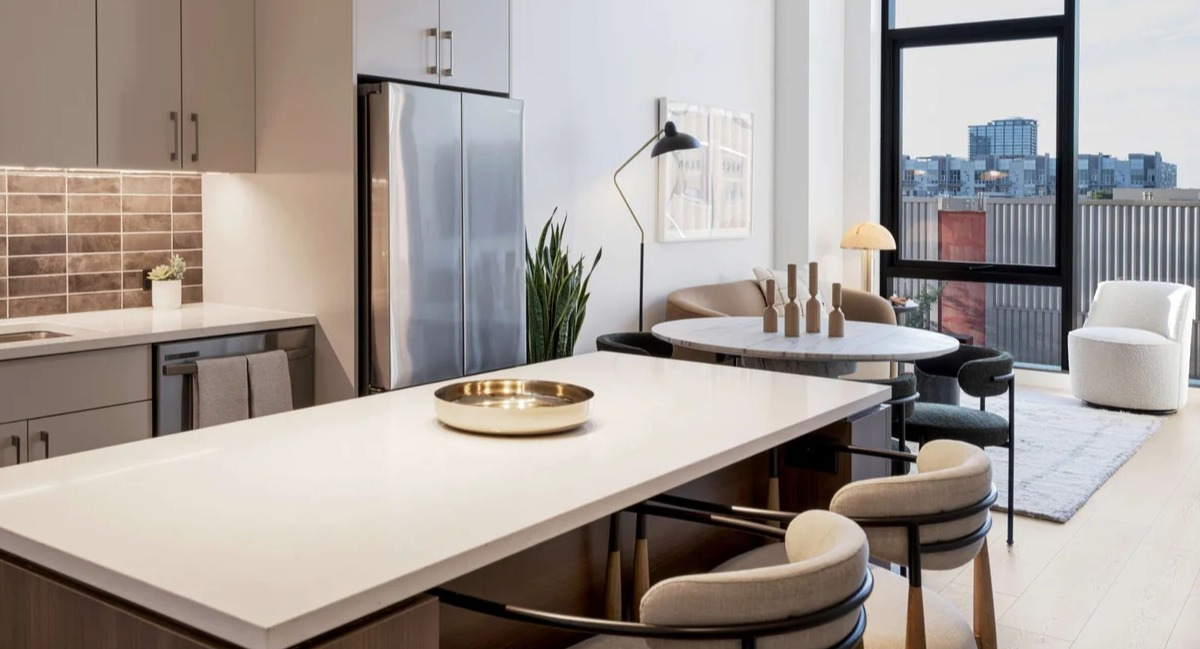 Modern apartment kitchen and dining area at Coppia in Chicago, featuring a spacious island, sleek appliances, and city views