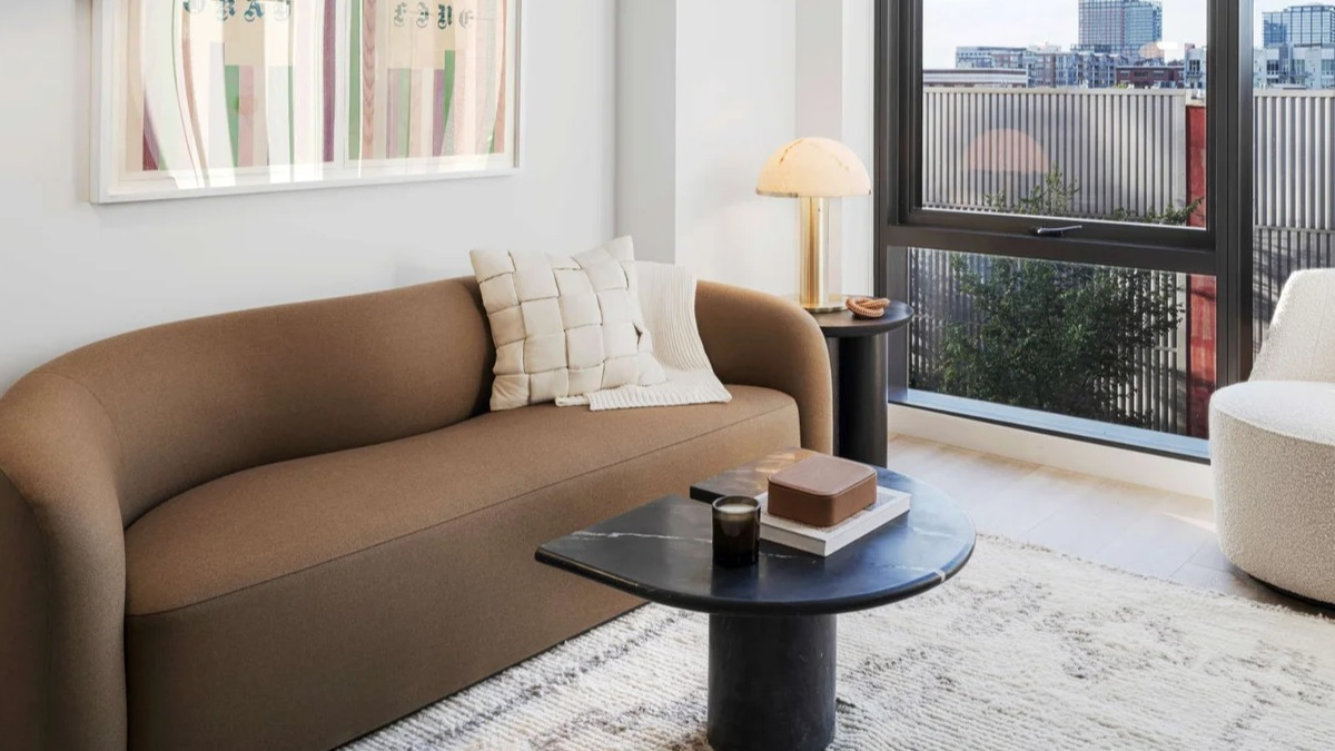 Cozy living room at Coppia apartments in Chicago with a stylish brown sofa, contemporary decor, and large windows