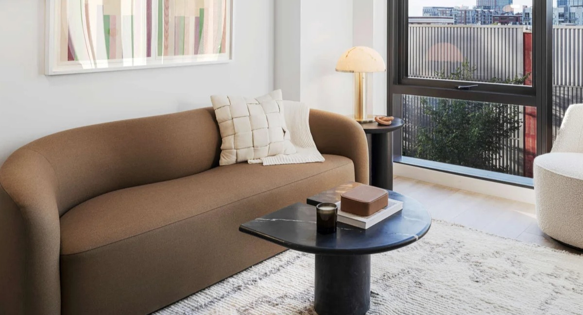 Cozy living room at Coppia apartments in Chicago with a stylish brown sofa, contemporary decor, and large windows