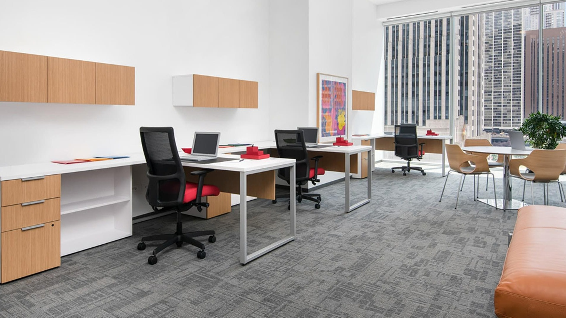 Bright coworking business suite with modern desks, task chairs, and large windows overlooking downtown at Optima Signature apartments in Chicago