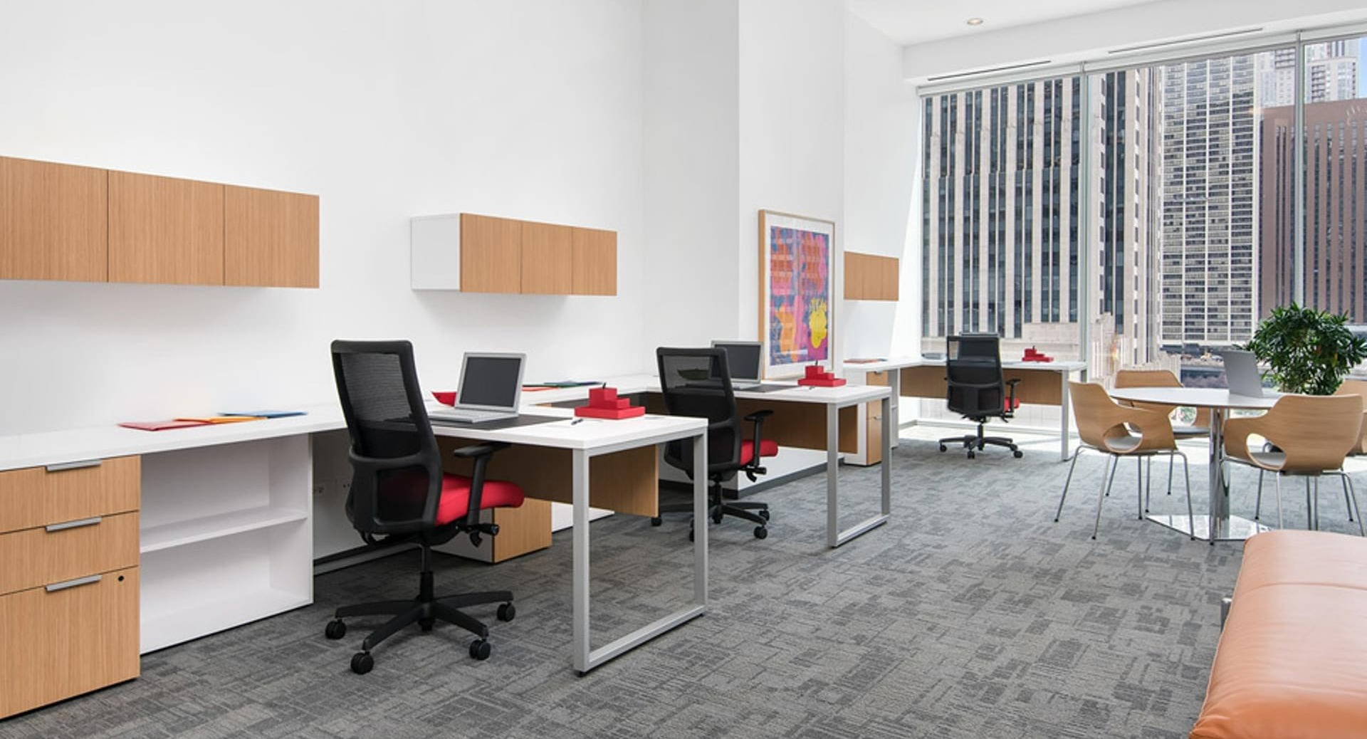 Bright coworking business suite with modern desks, task chairs, and large windows overlooking downtown at Optima Signature apartments in Chicago