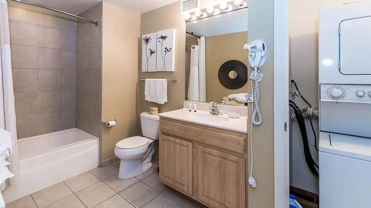 Full bathroom with a shower-tub combo, vanity, and a stacked in-unit washer and dryer for convenience at Echelon at K Station in Chicago