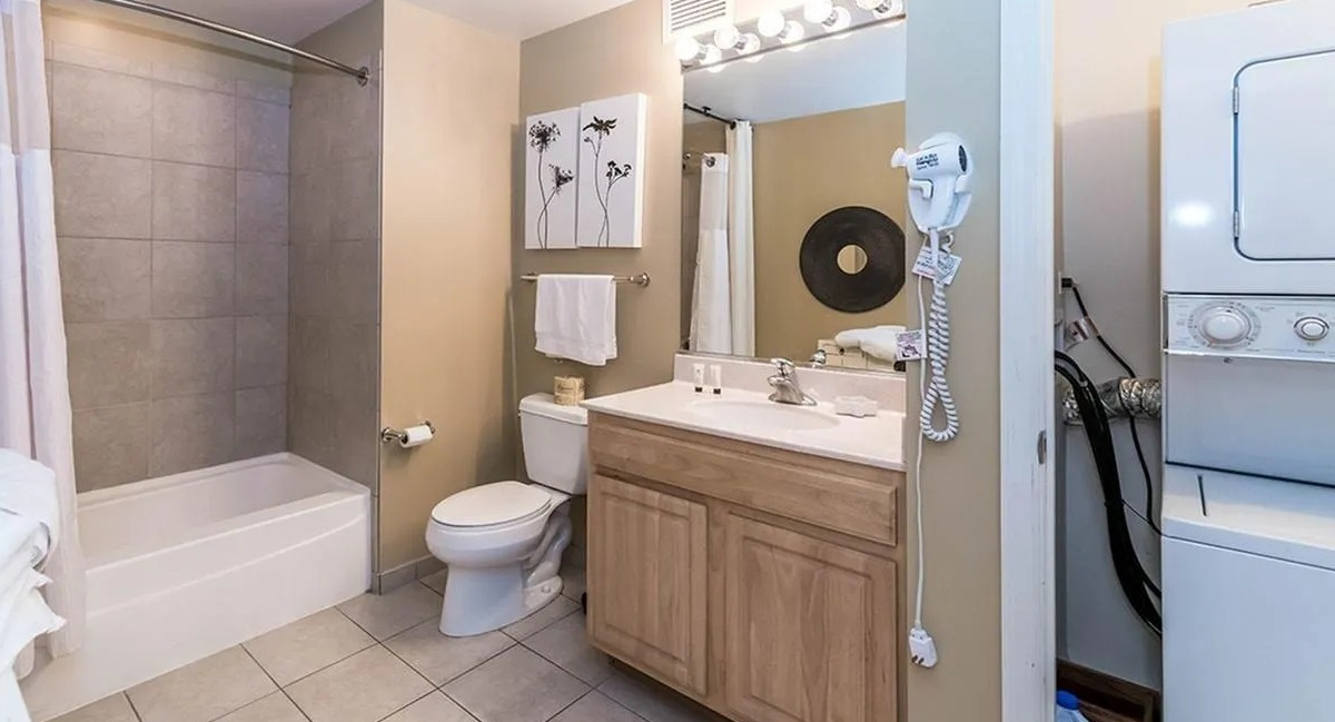 Full bathroom with a shower-tub combo, vanity, and a stacked in-unit washer and dryer for convenience at Echelon at K Station in Chicago
