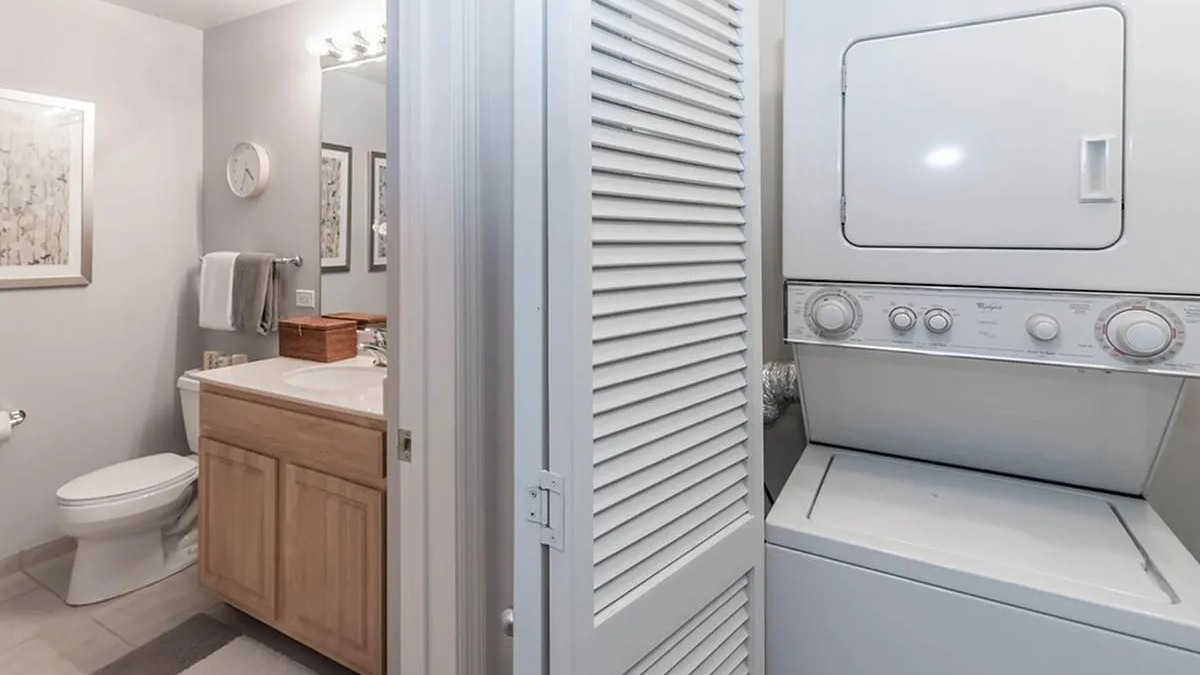 Bright bathroom with a vanity and toilet, adjacent to a stacked in-unit washer and dryer at Echelon at K Station in Chicago