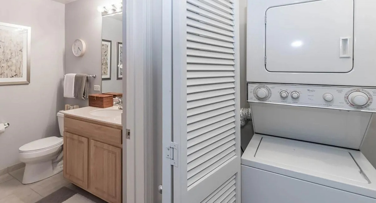 Bright bathroom with a vanity and toilet, adjacent to a stacked in-unit washer and dryer at Echelon at K Station in Chicago