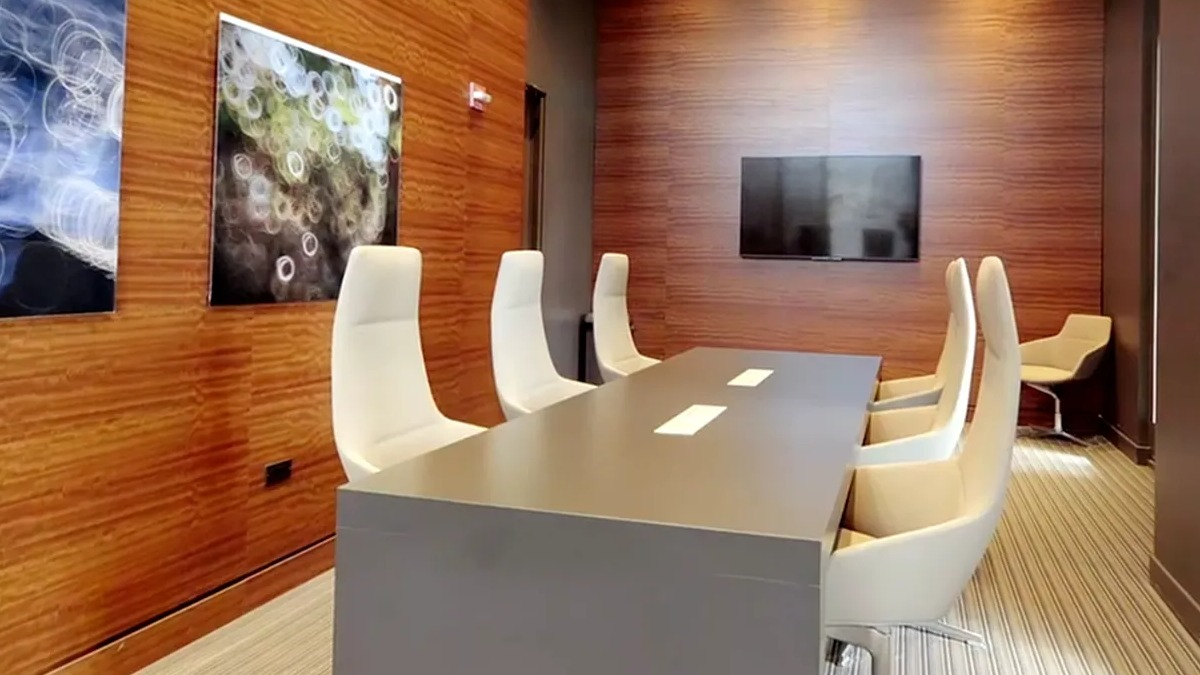 Modern conference room with a large table, white chairs, and wood-paneled walls at Echelon at K Station in Chicago