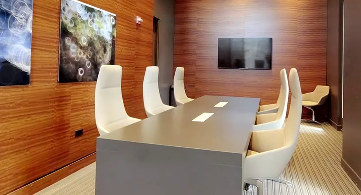 Modern conference room with a large table, white chairs, and wood-paneled walls at Echelon at K Station in Chicago