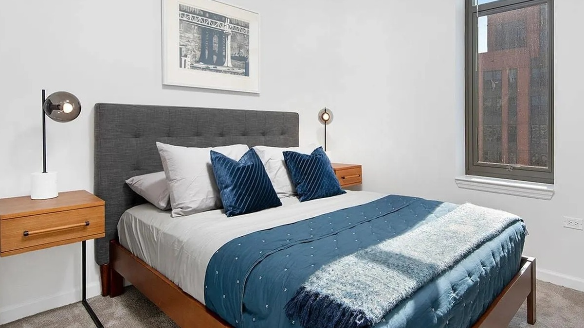 Cozy bedroom with a queen-sized bed, two nightstands, and a large window bringing in natural light at Echelon at K Station in Chicago