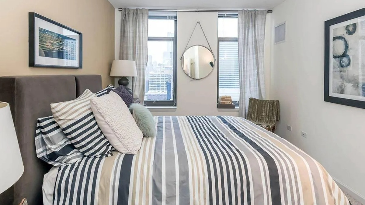 Cozy bedroom featuring a comfortable bed with striped bedding, a large window, and modern decor at Echelon at K Station in Chicago
